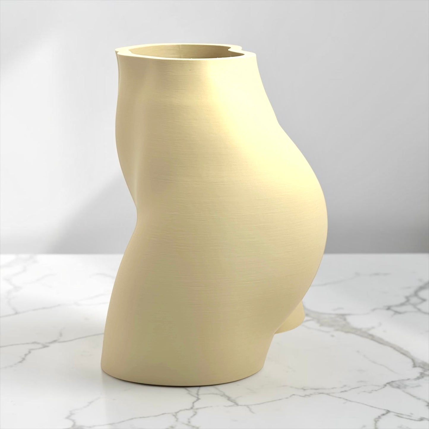 Beige vase shaped like a sexy butt on a marble surface with a gray background
