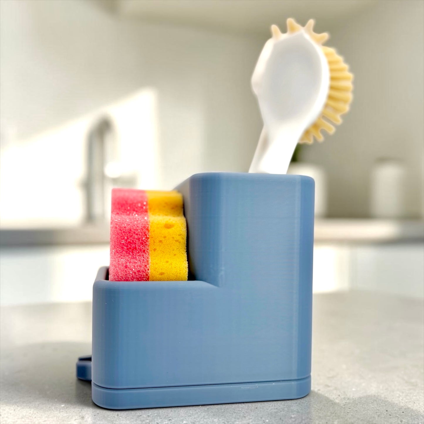 Blue kitchen sponge holder with sponges and scrubber on a countertop.