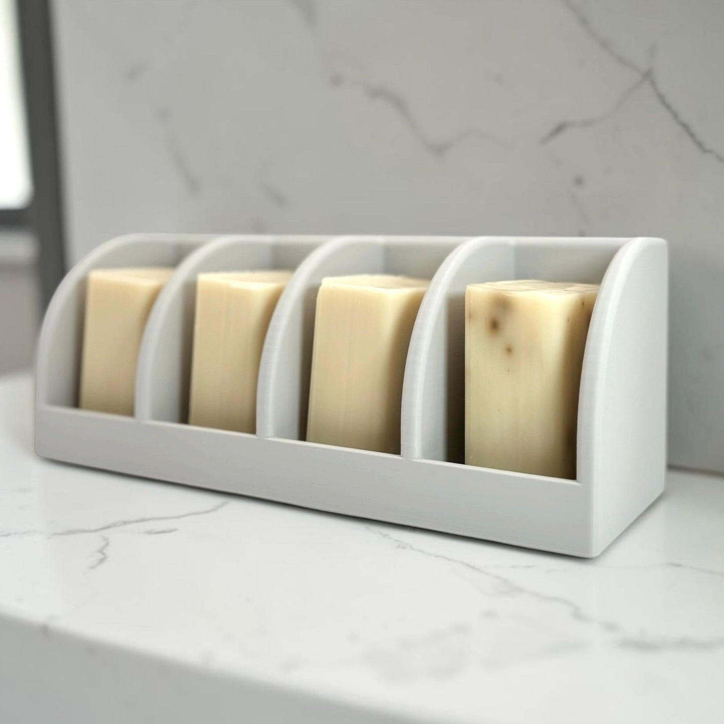 light gray soap holder with four bars of soap on a marble surface