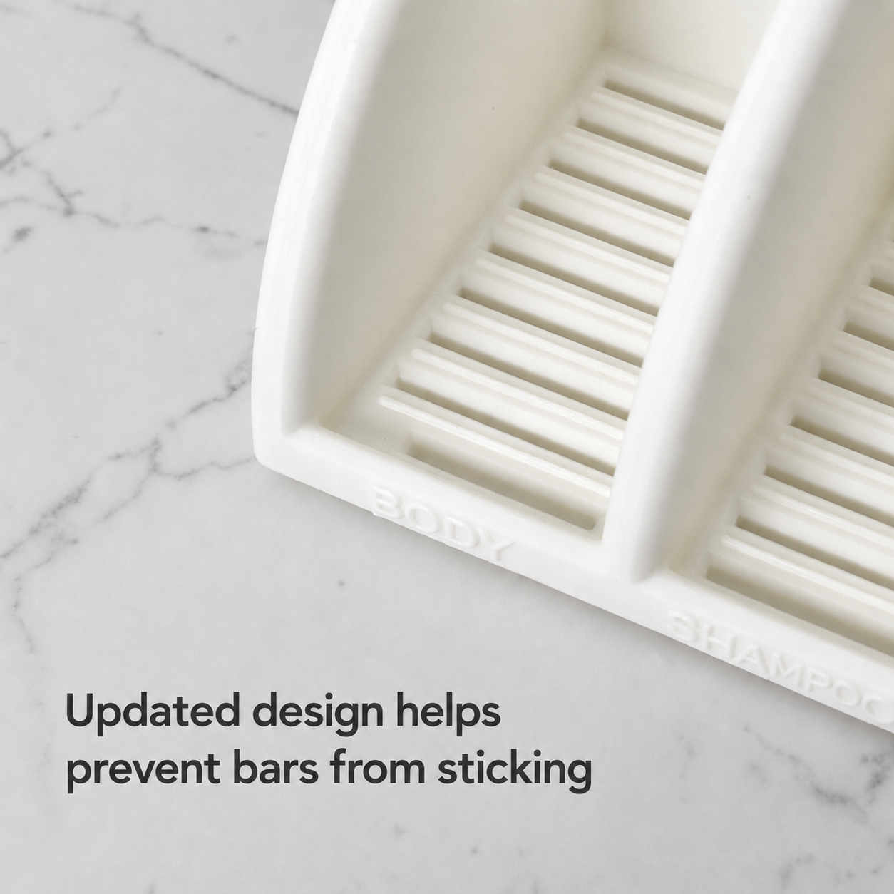 White soap dish with slotted design on a marble surface indicating design prevents bars from sticking