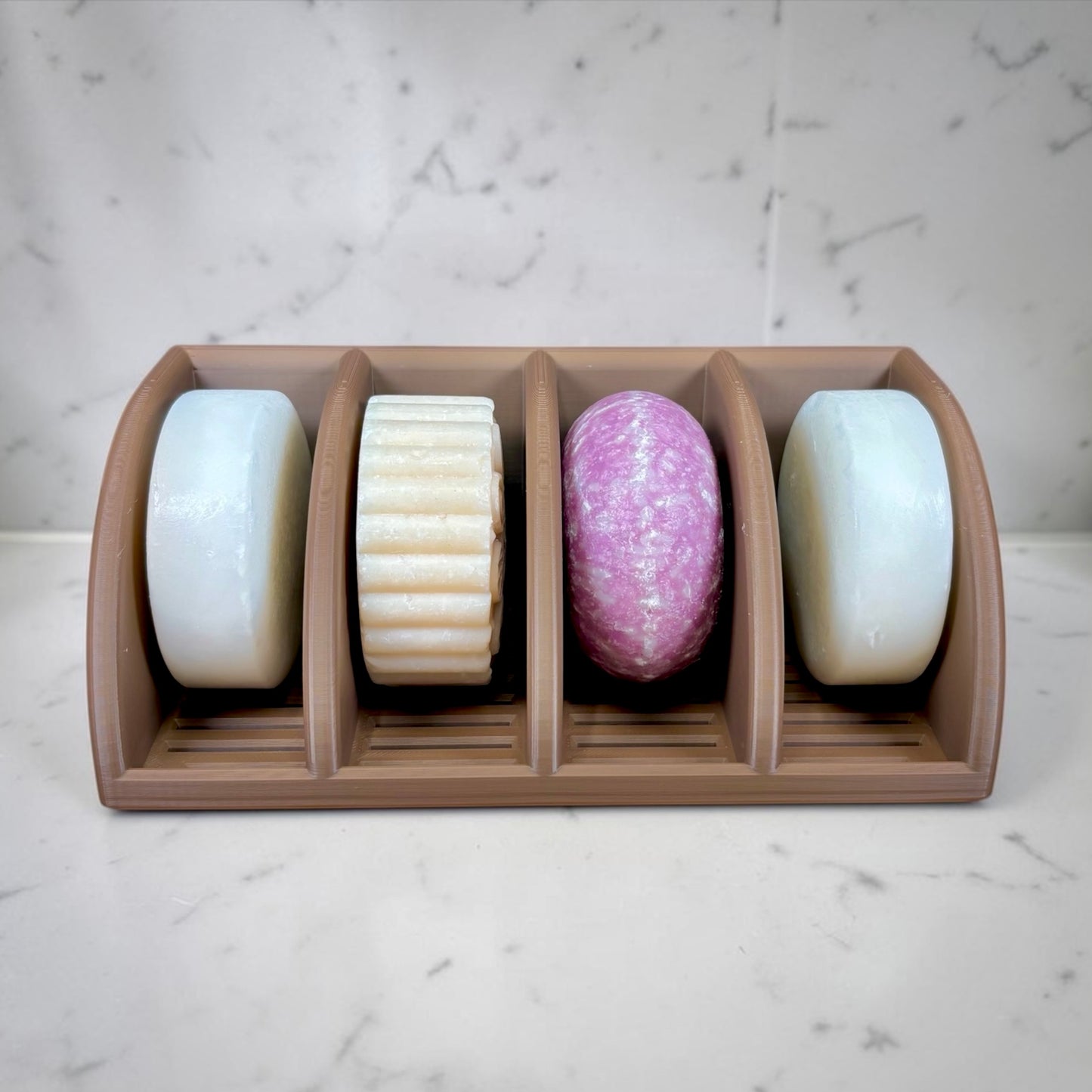 Four soaps in a brown holder on a marble surface