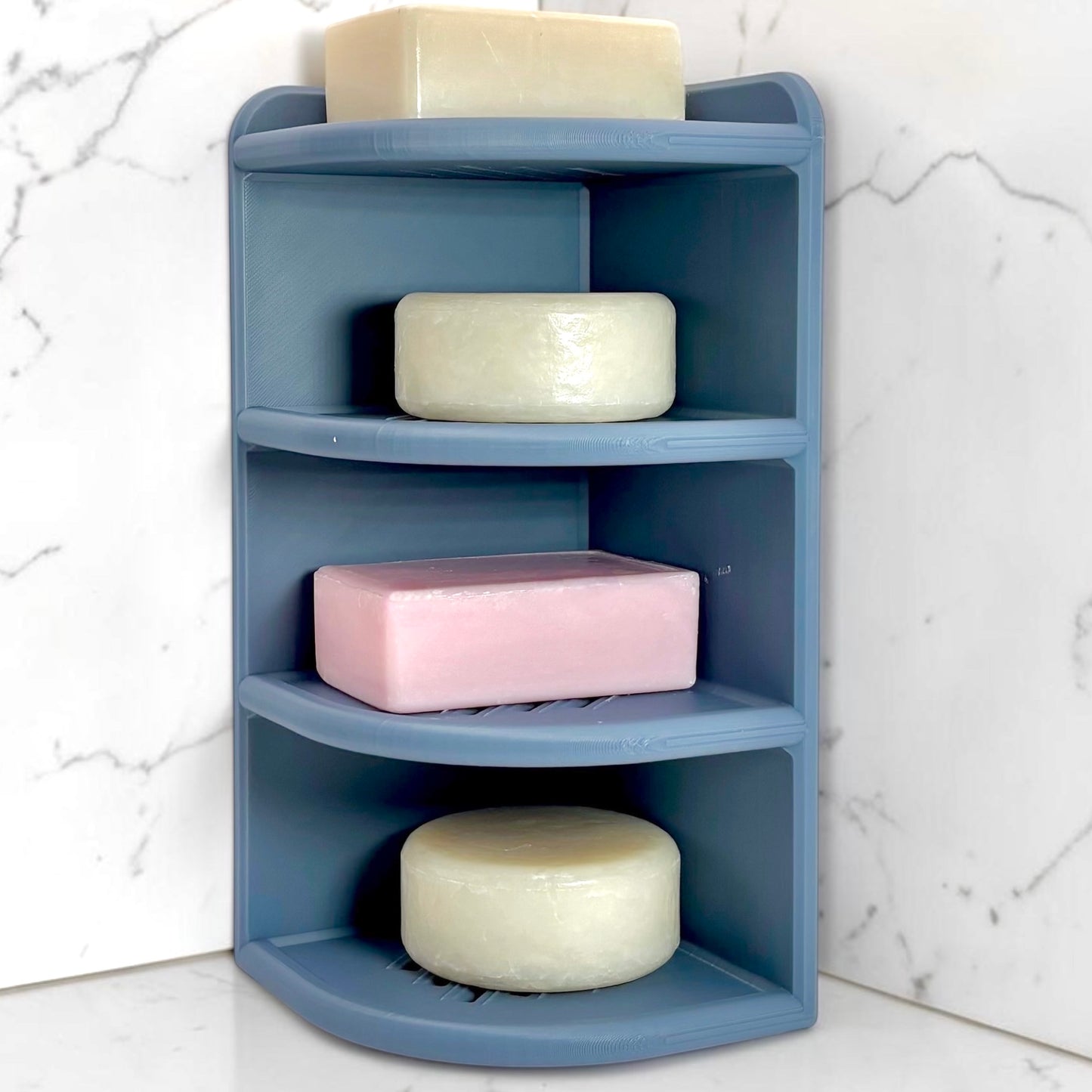 Blue corner shelf with soap bars on a marble bathroom floor