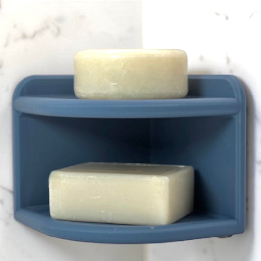 Blue corner soap holder with two bars of soap on a white marble background