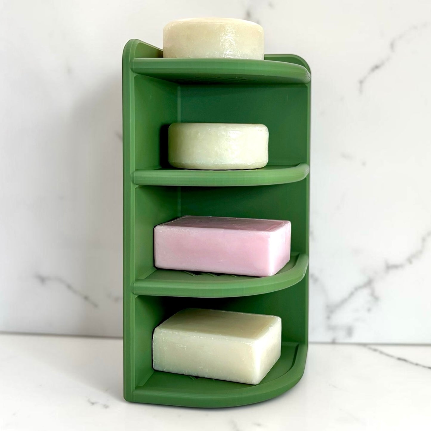 Green corner soap holder with four soap bars on a marble background