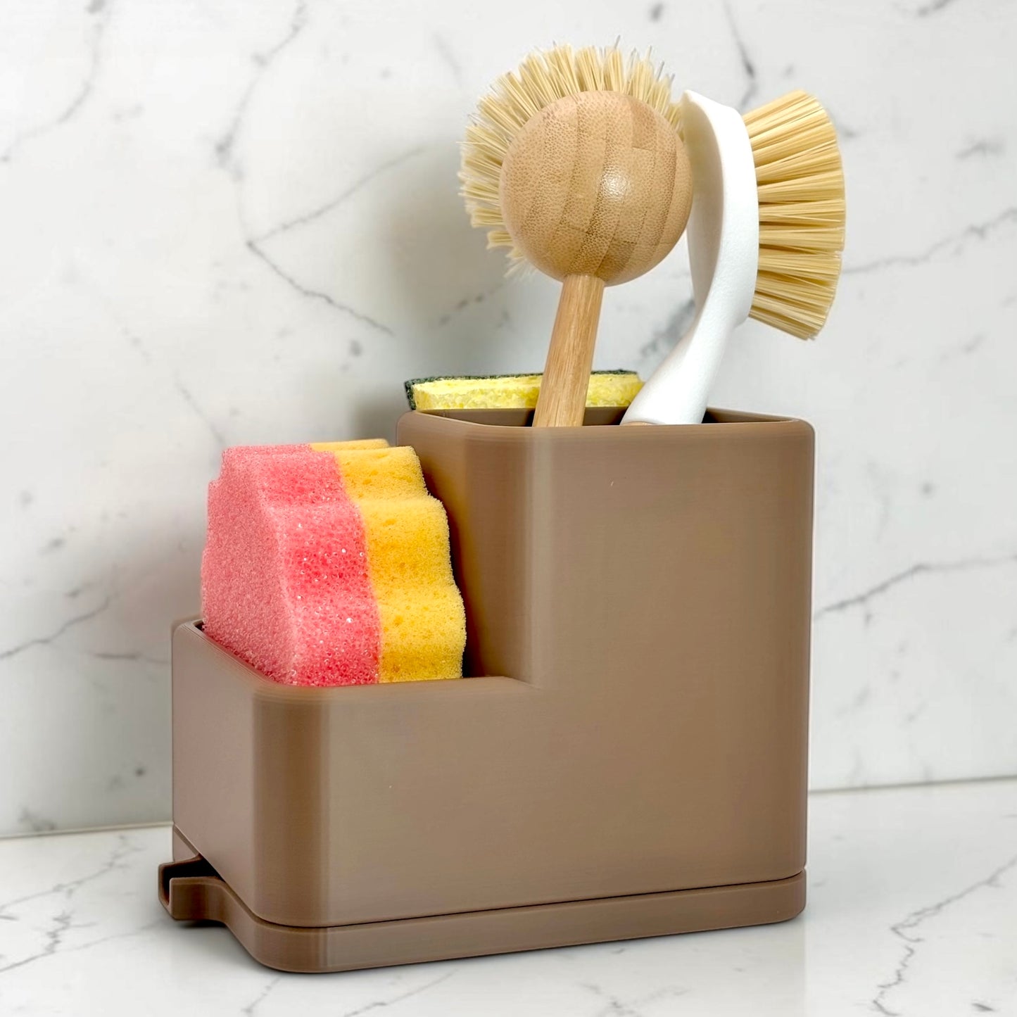 Brown caddy with sponges and cleaning brushes on a marble countertop