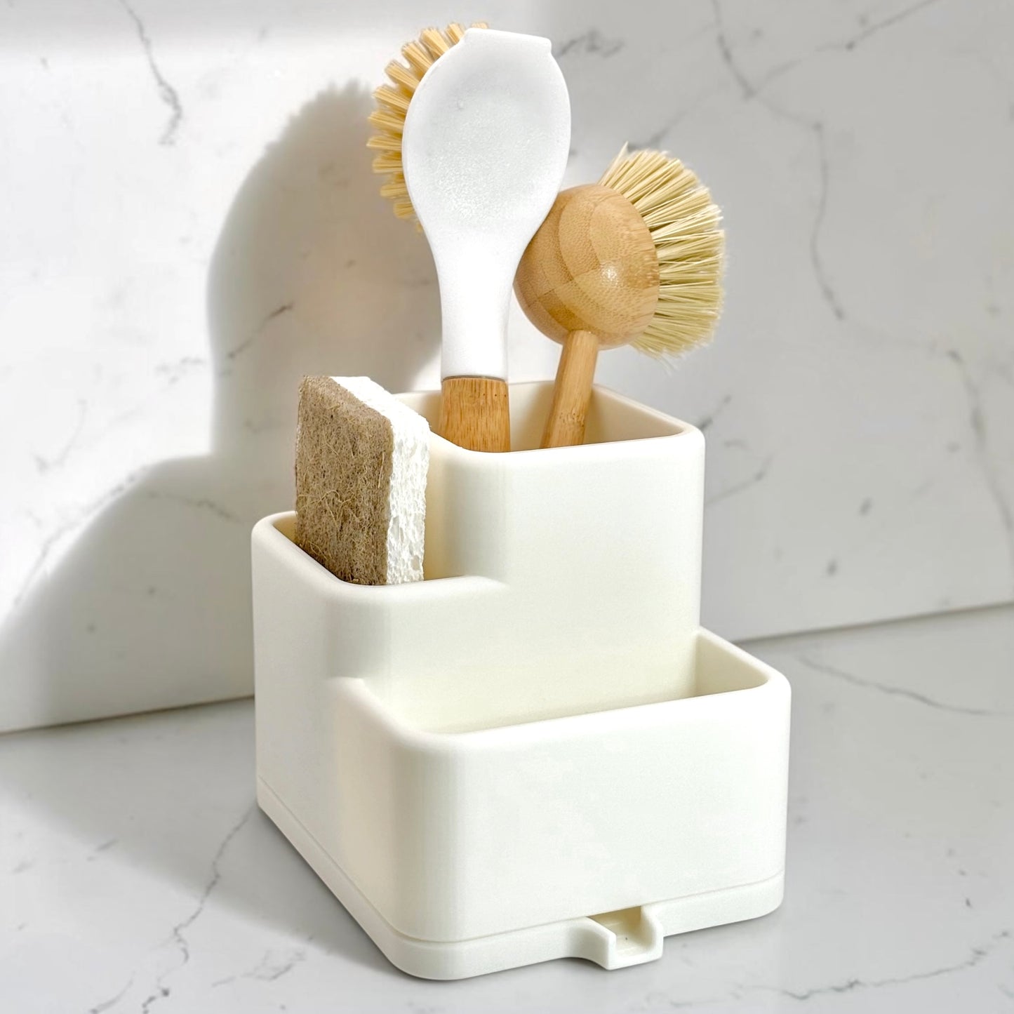White dishwashing brush holder with various cleaning tools on a marble surface
