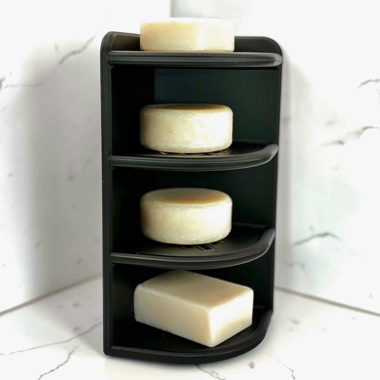 Black corner shelf with soap bars on a marble surface