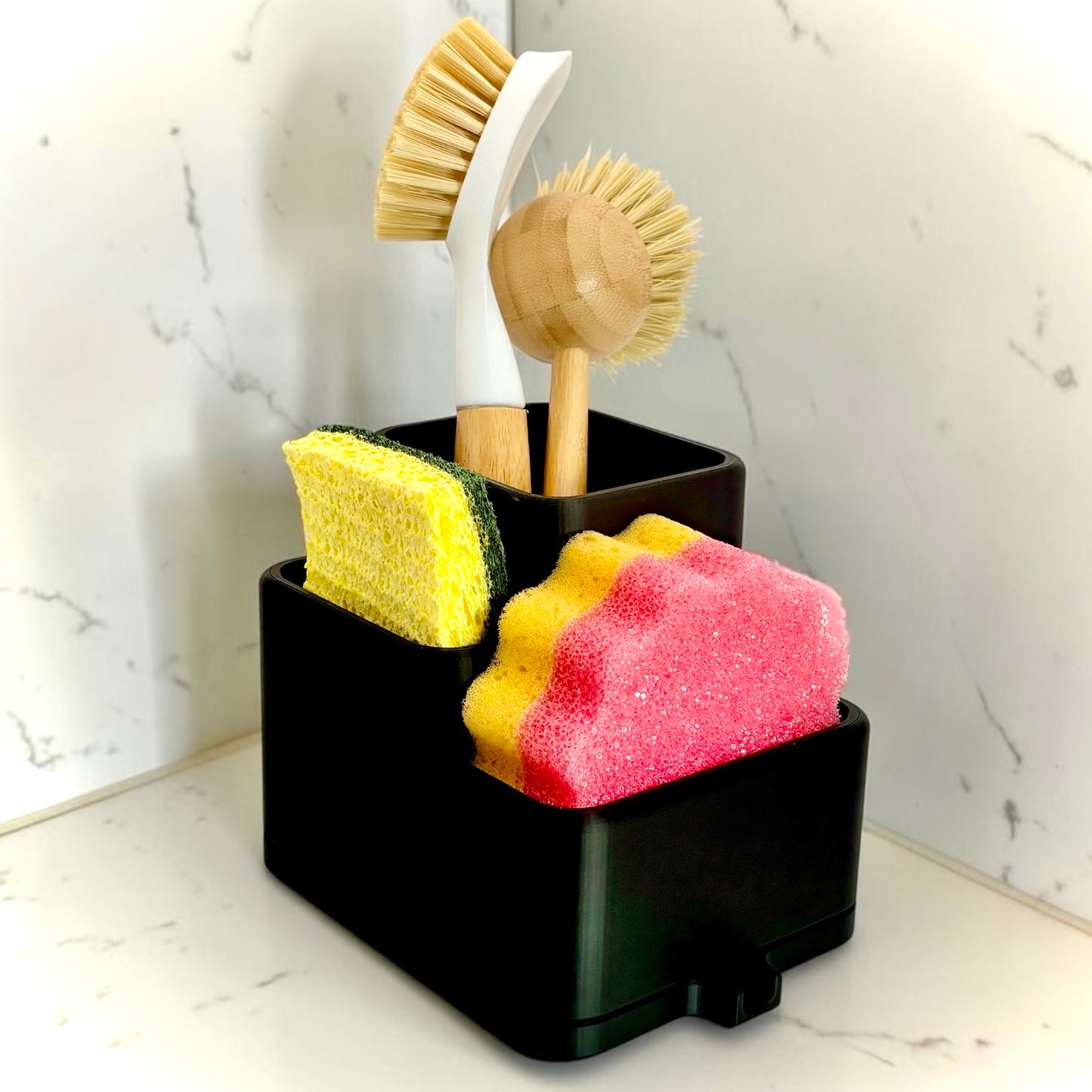 Black caddy with sponges and brushes on a marble countertop