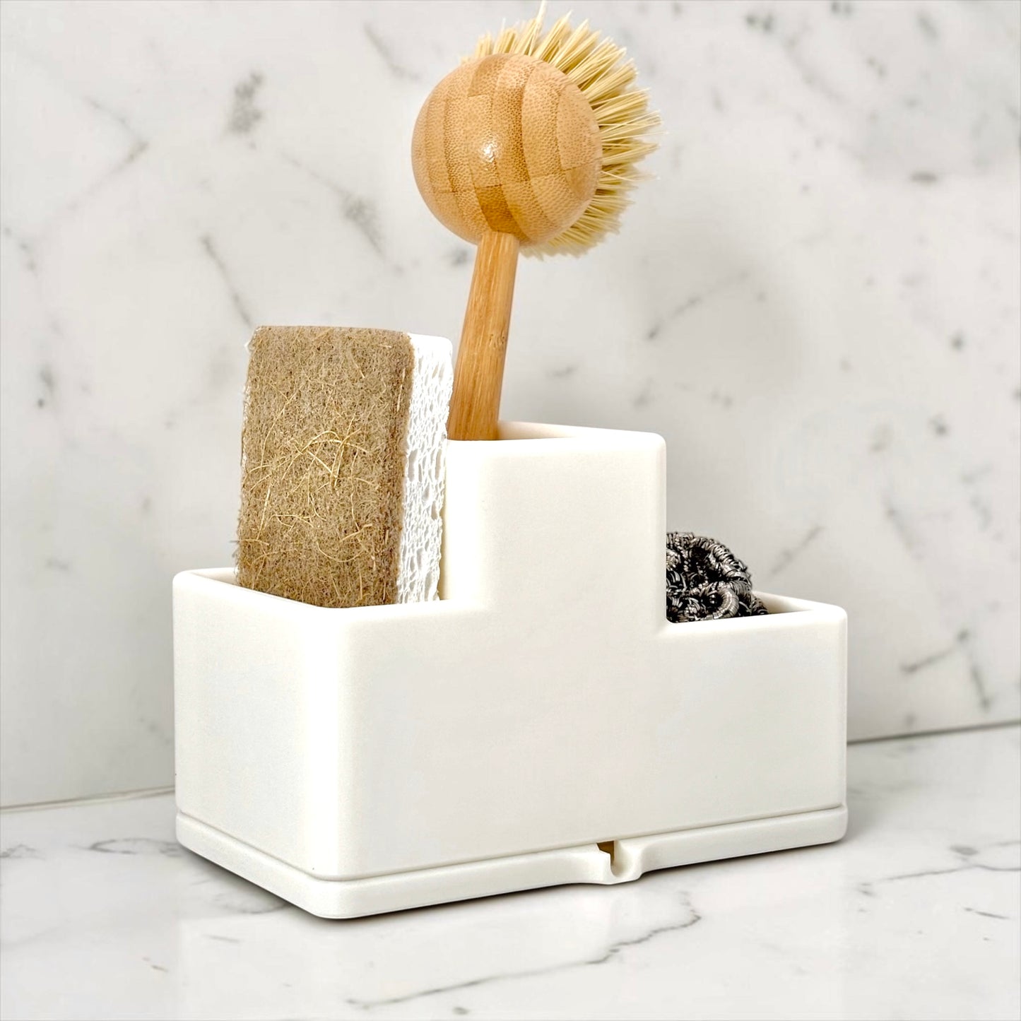 White sink caddy with a wooden scrubber and sponge on a marble background