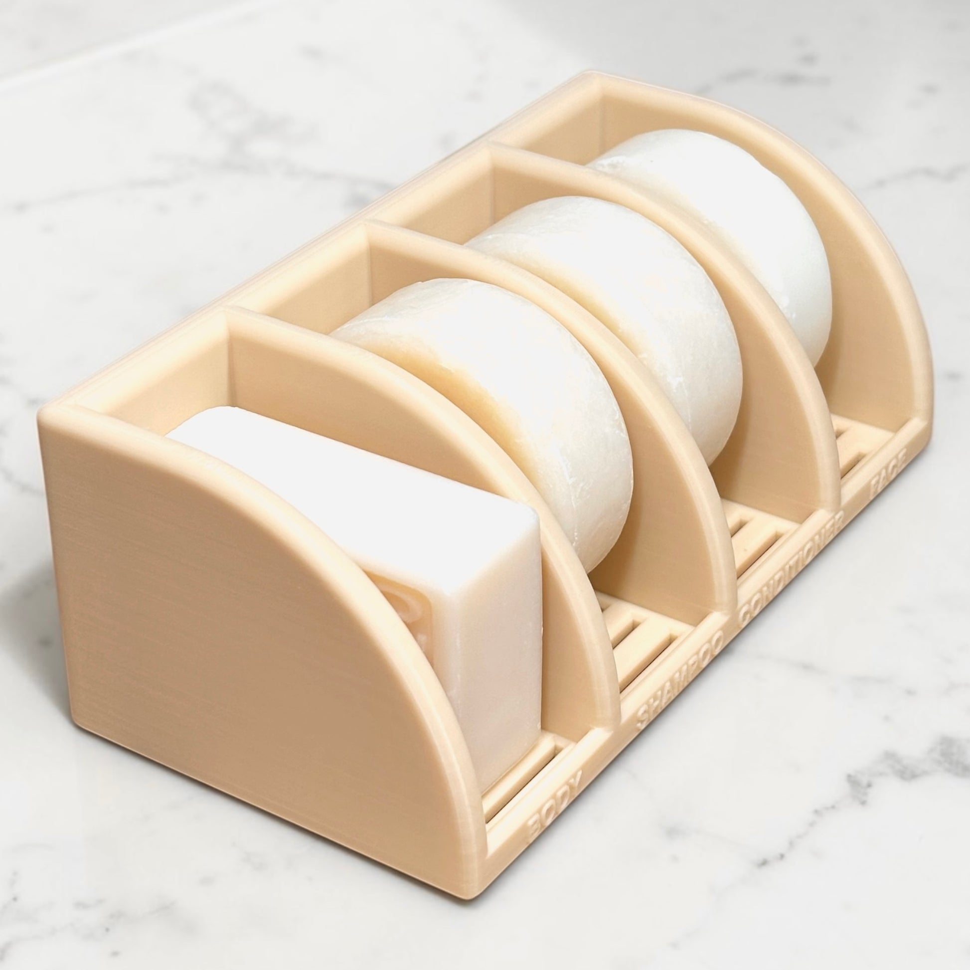 Beige soap holder with four bars of soap on a marble surface