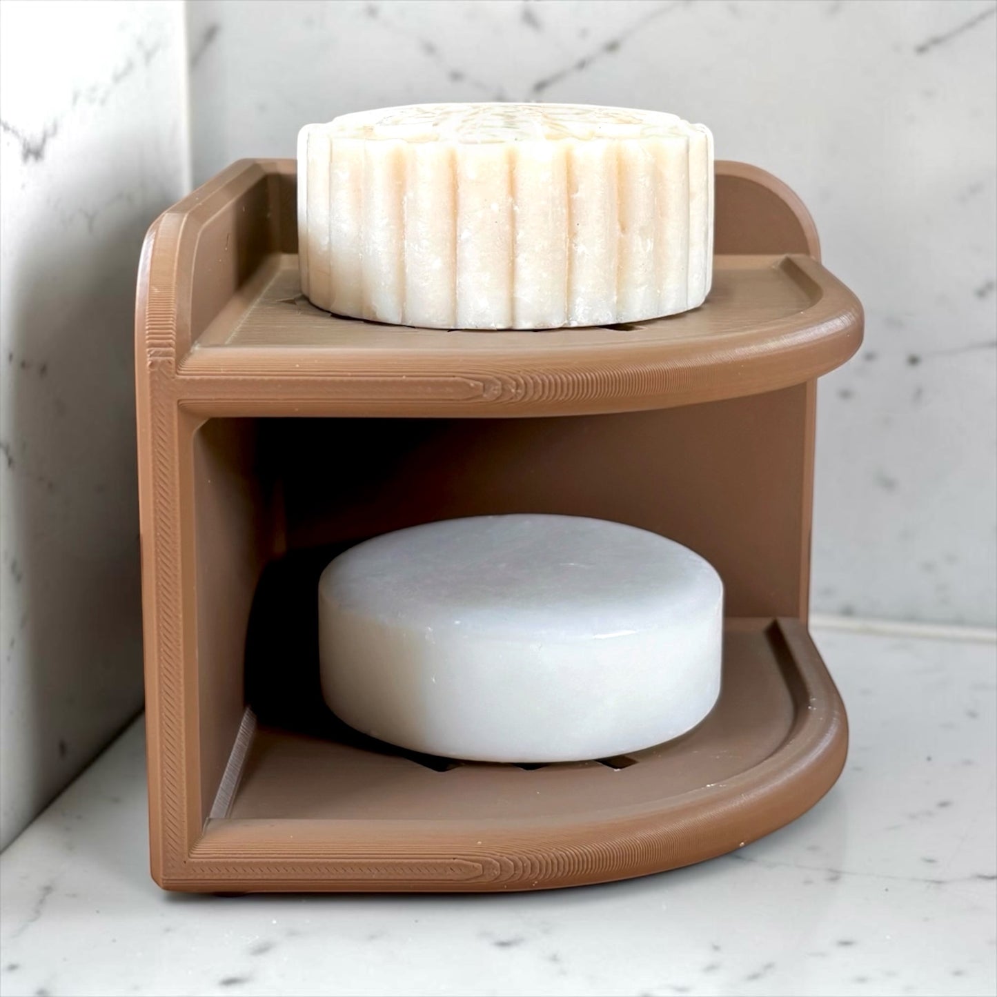 Brown soap holder with two bars of soap on a marble surface
