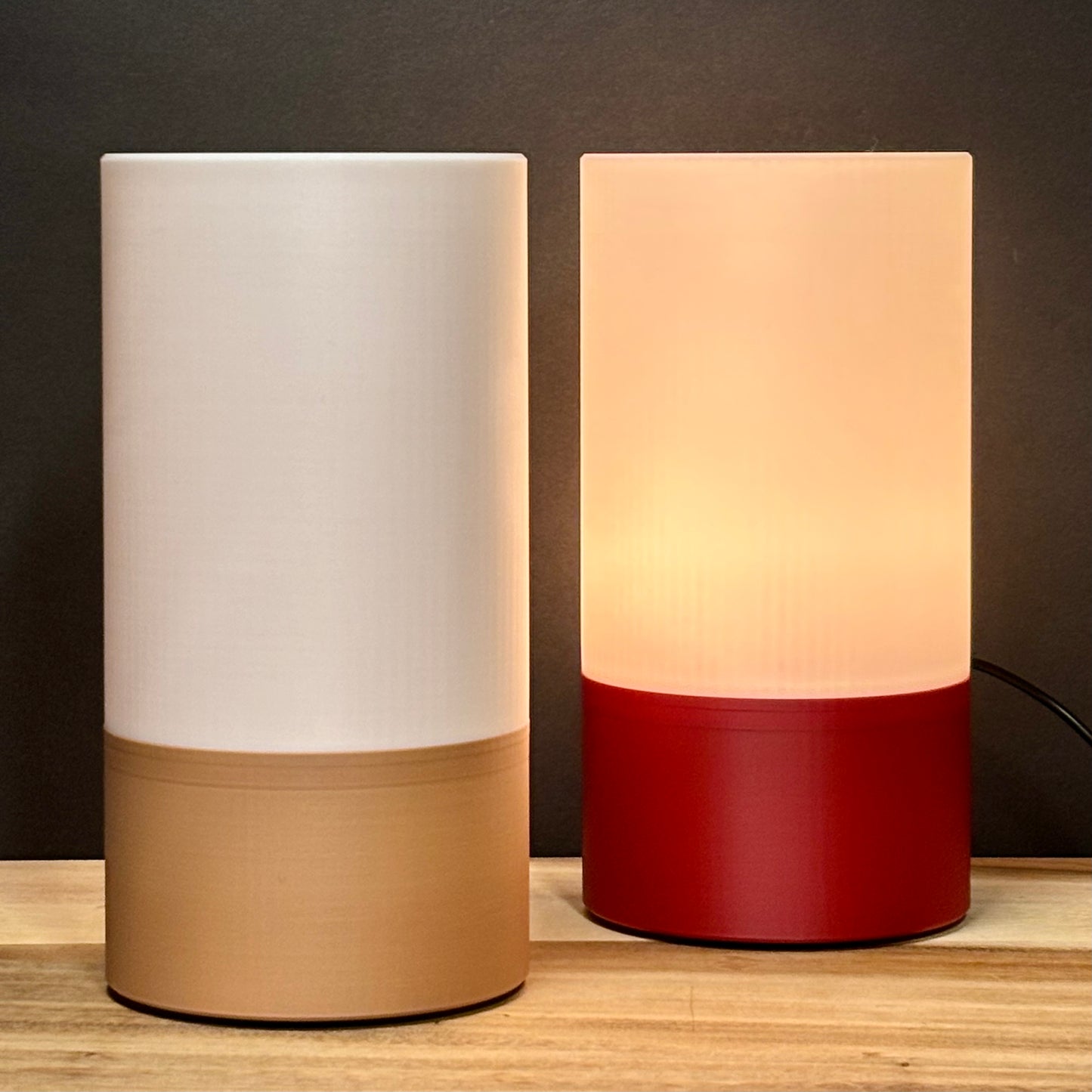 Two cylindrical lamps with different color schemes on a wooden surface.