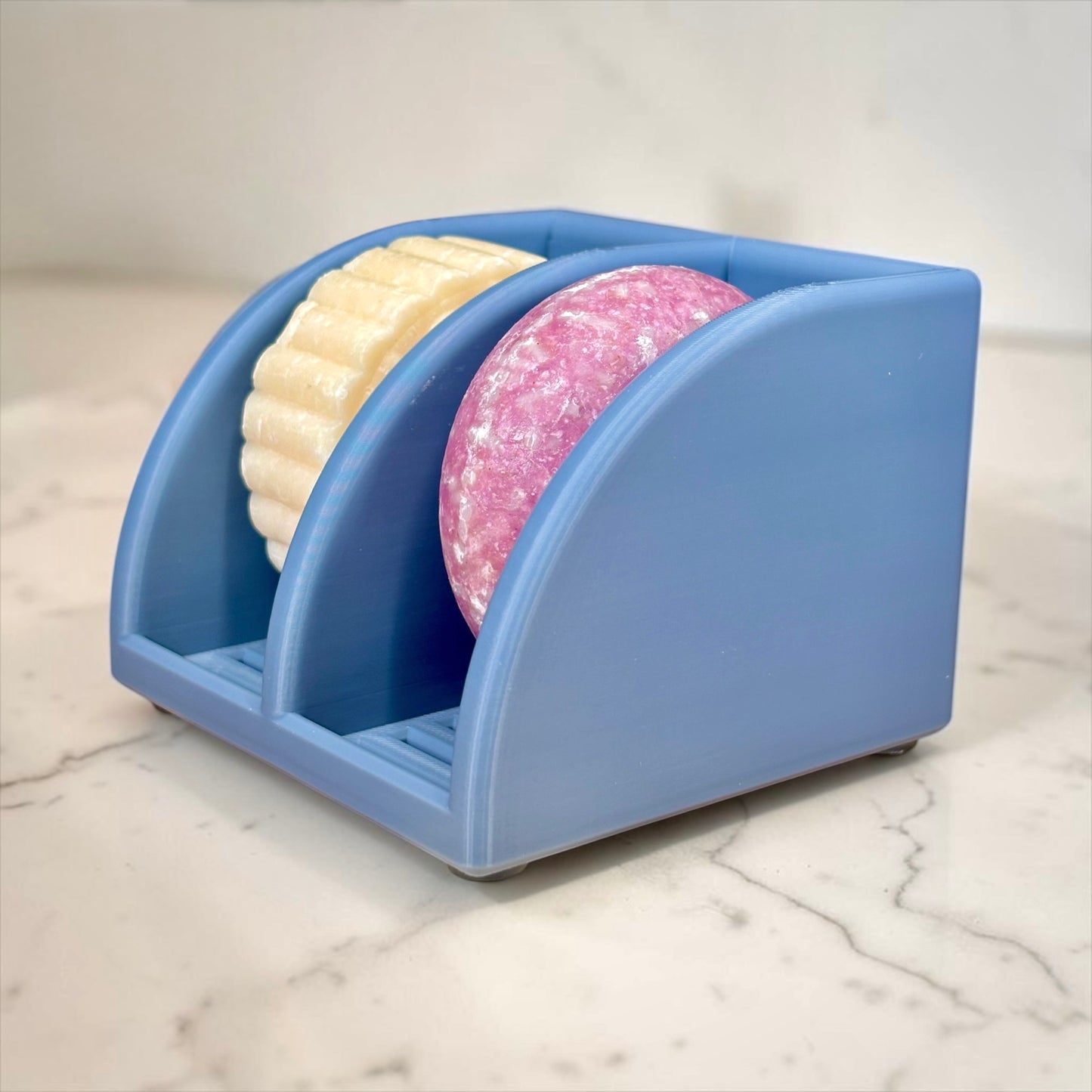 Misty Blue soap holder with two bars of soap on a marble surface
