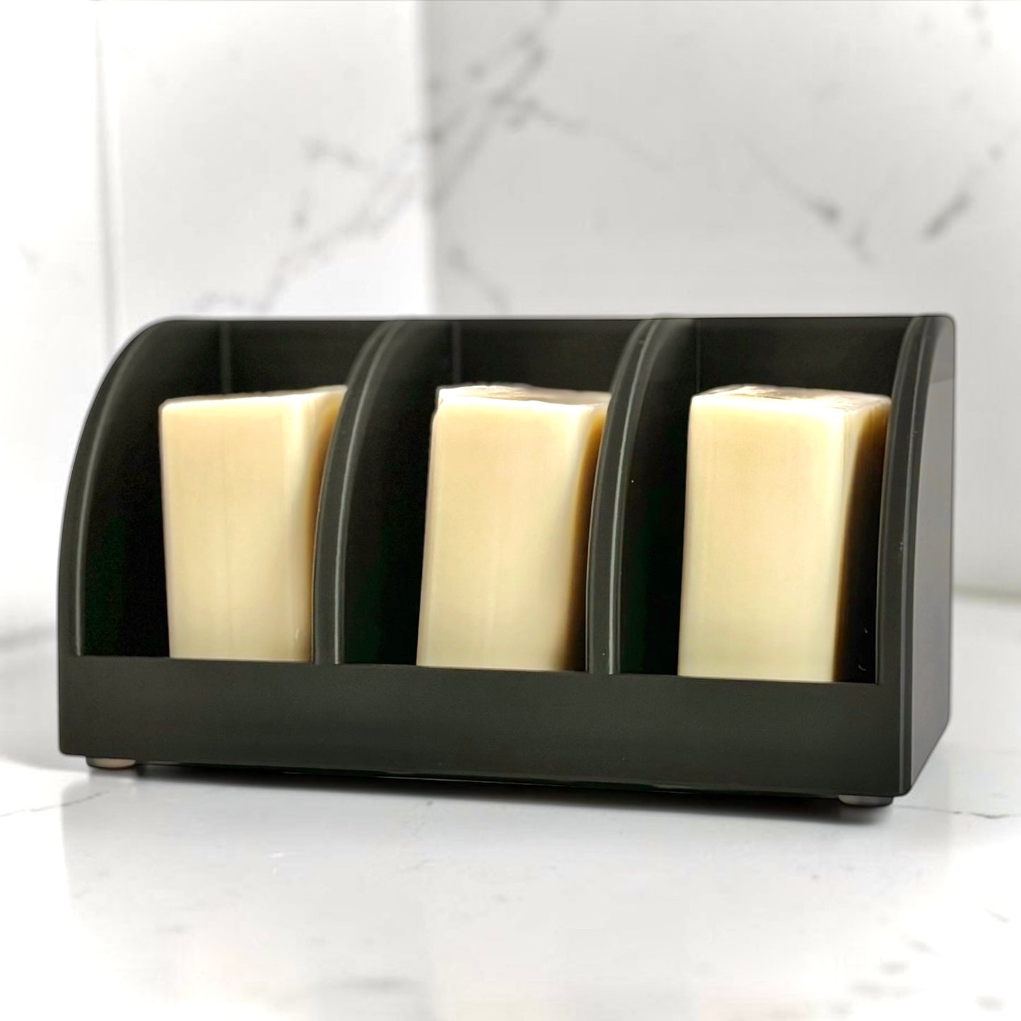 Black soap holder with three bars of soap on a white surface.