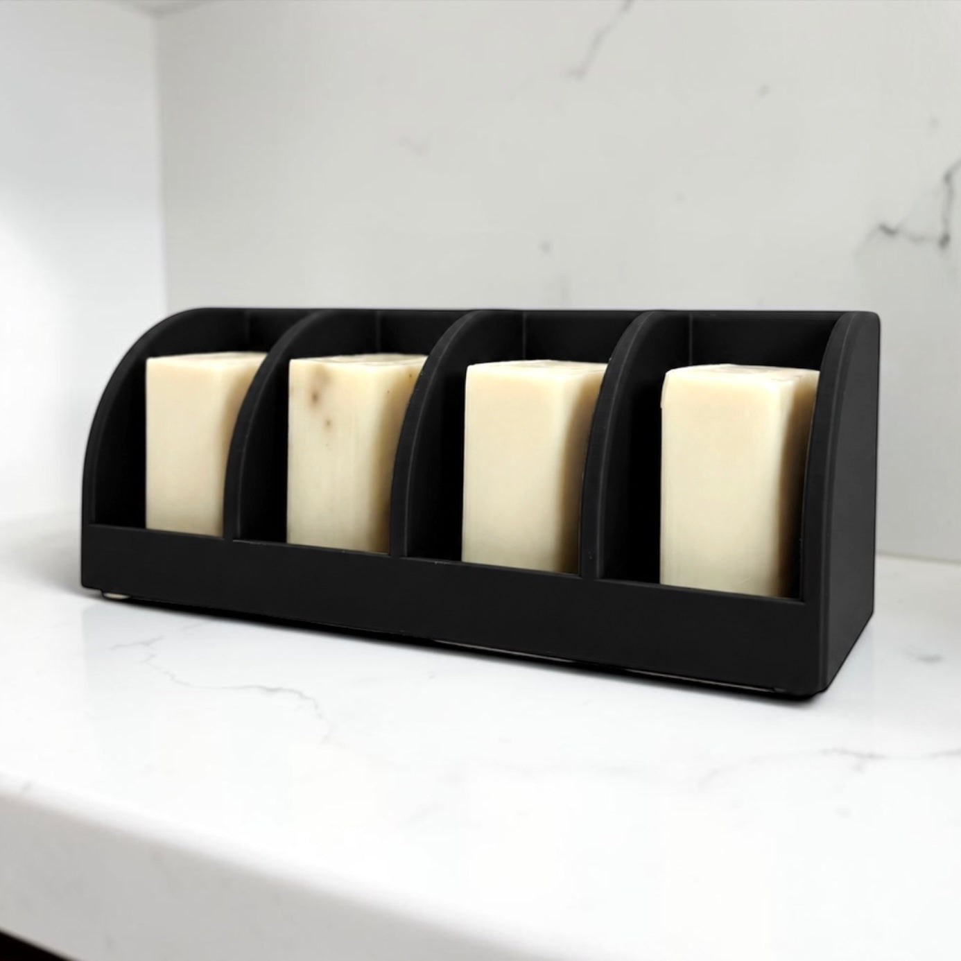 Black soap holder with four bars of soap on a white surface.