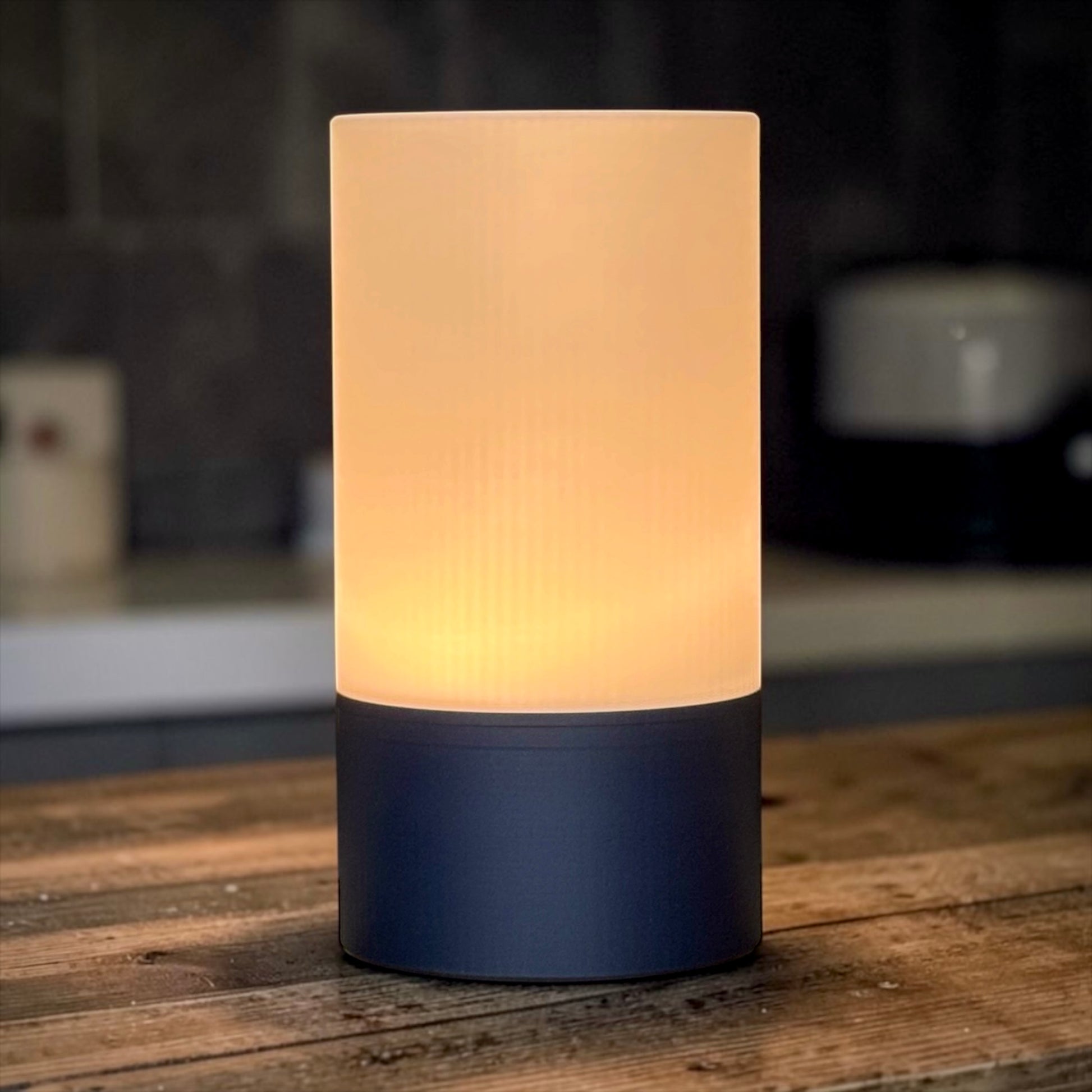 Cylindrical lamp with a textured white shade and dark base on a wooden surface.