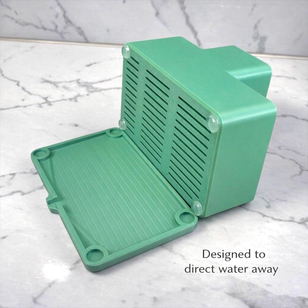 Green plastic enclosure with text 'Designed to direct water away' on a marble background