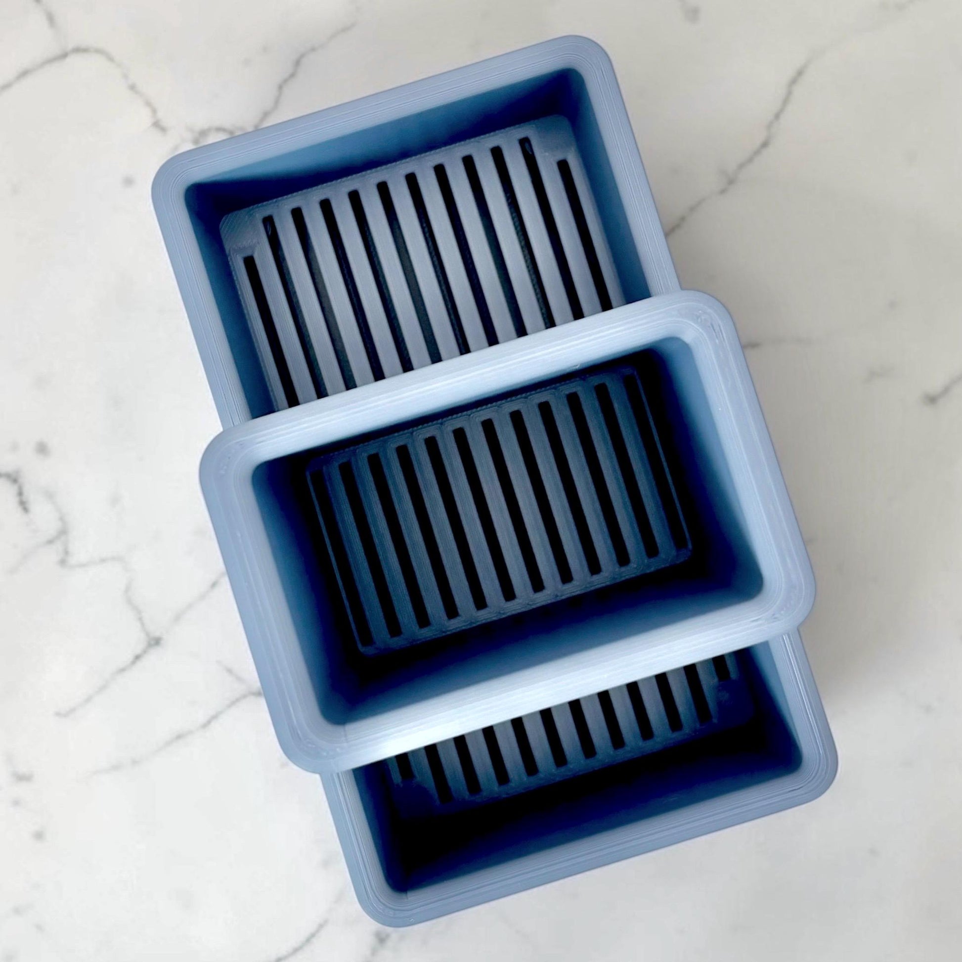 blue sink caddy viewed from top showing slotted drain holes on a marble surface