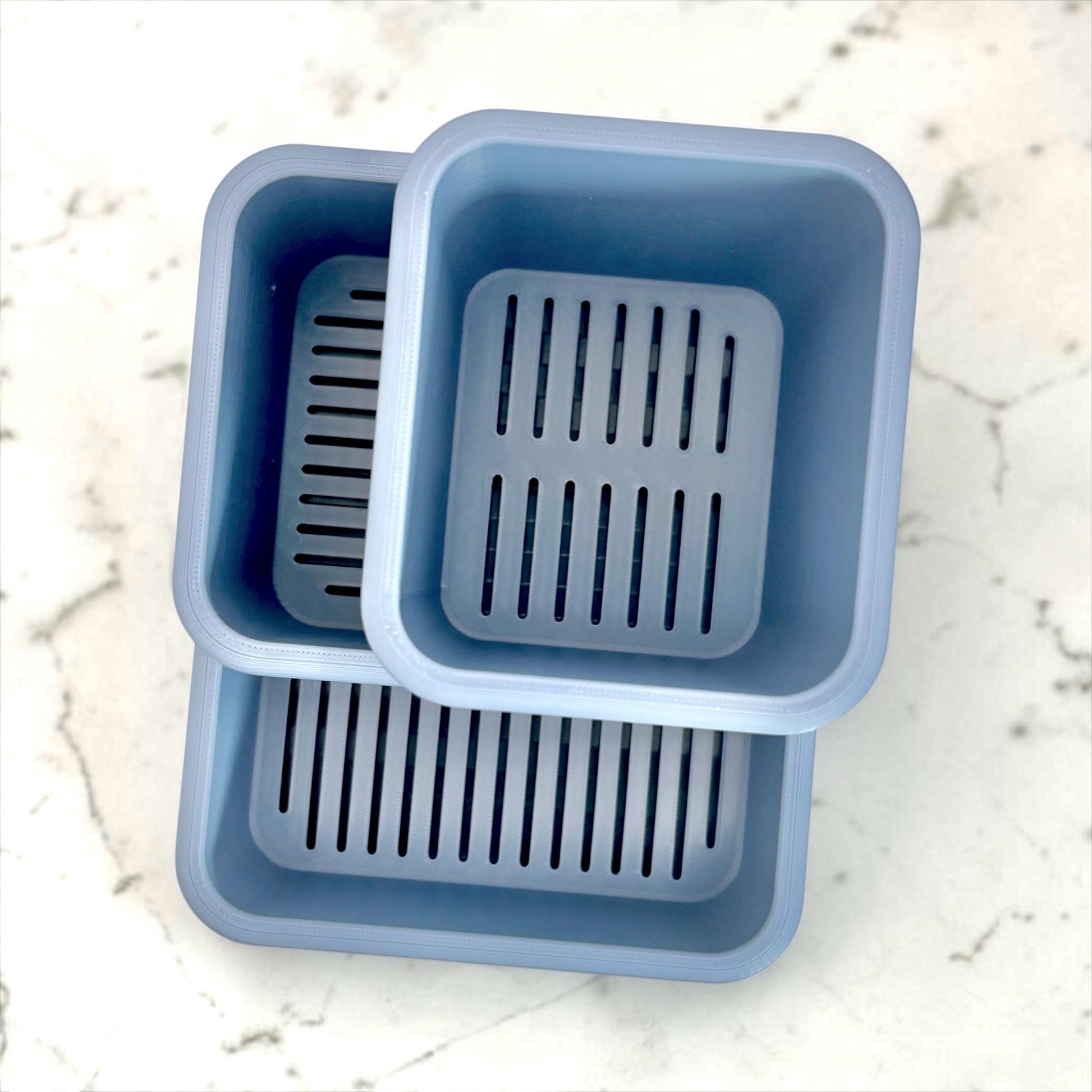 top view of an empty sink caddy with slotted designs on a marble surface