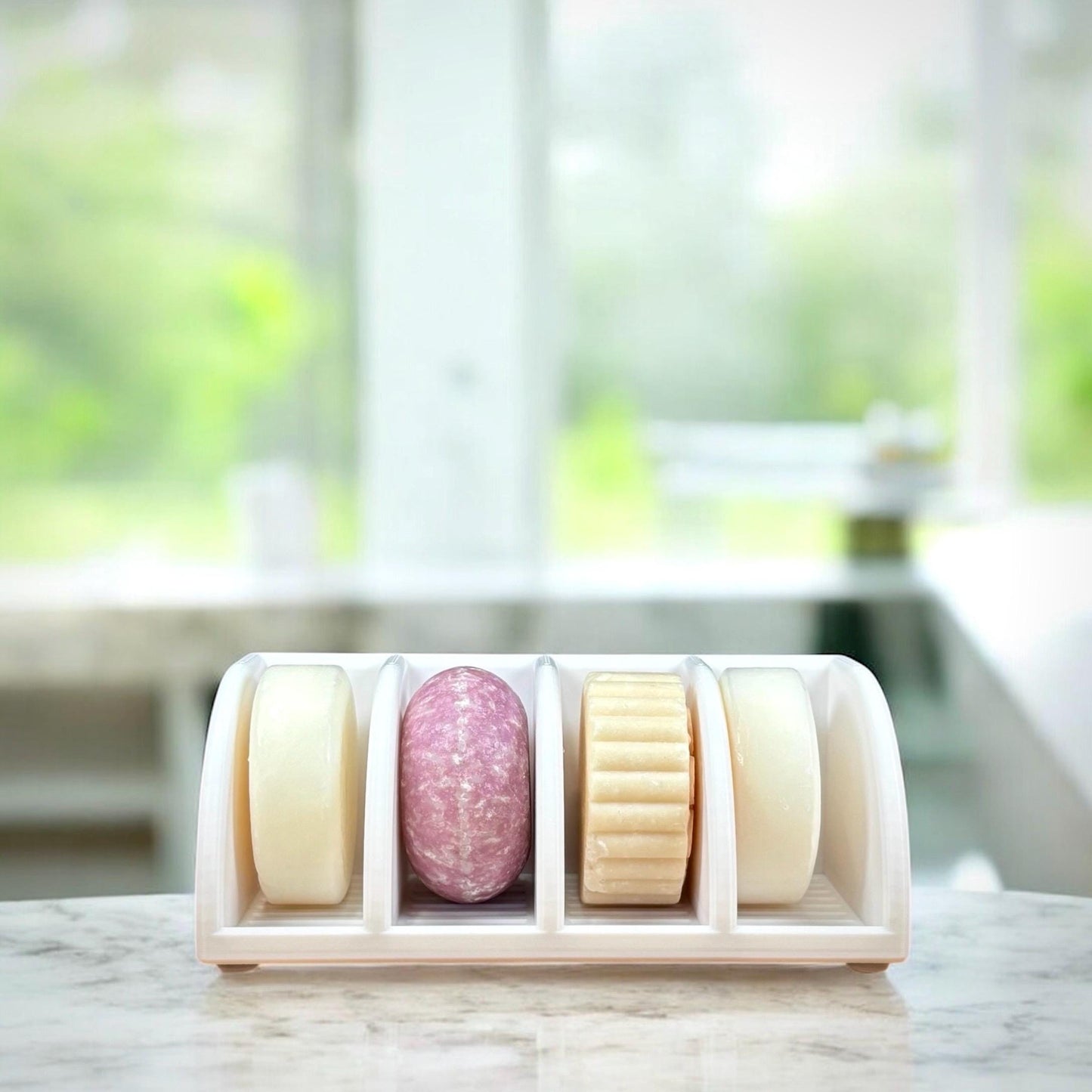 Set of colorful soap bars in a holder with a blurred greenery background