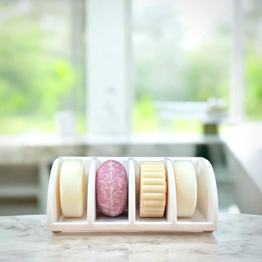 Set of colorful soap bars in a holder with a blurred greenery background