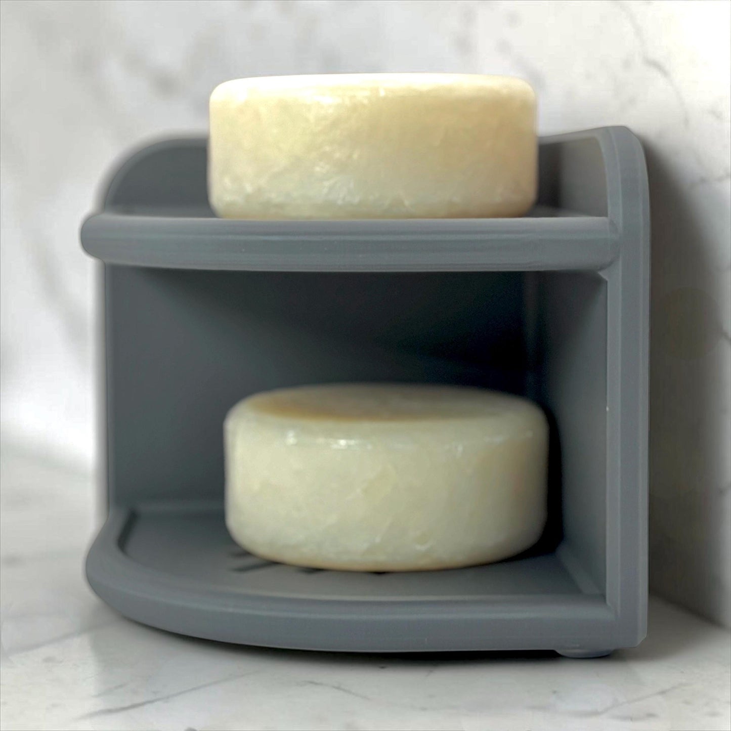 Two bars of soap on a gray tower shelf with a white background