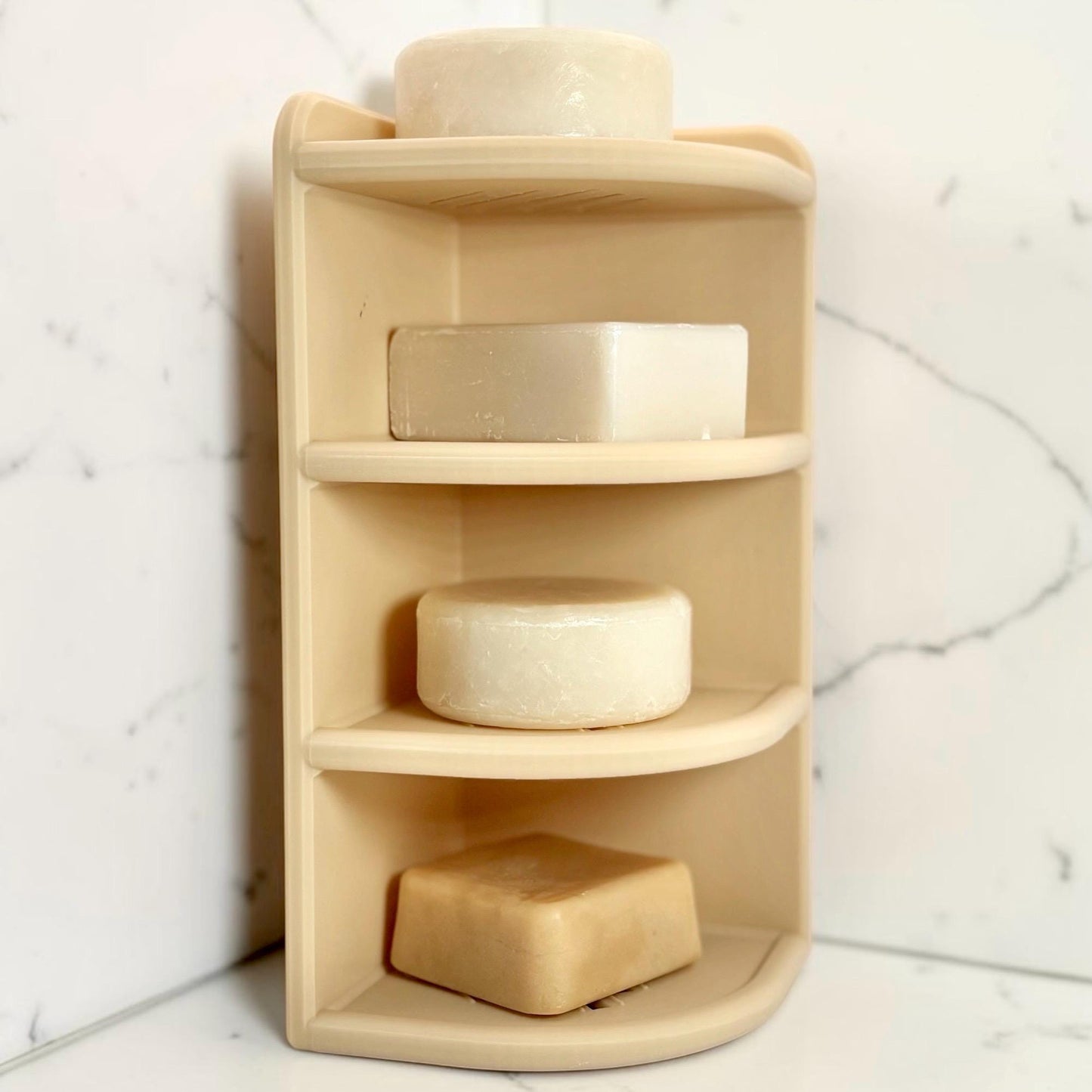 beige corner shelf with soap bars against a marble wall